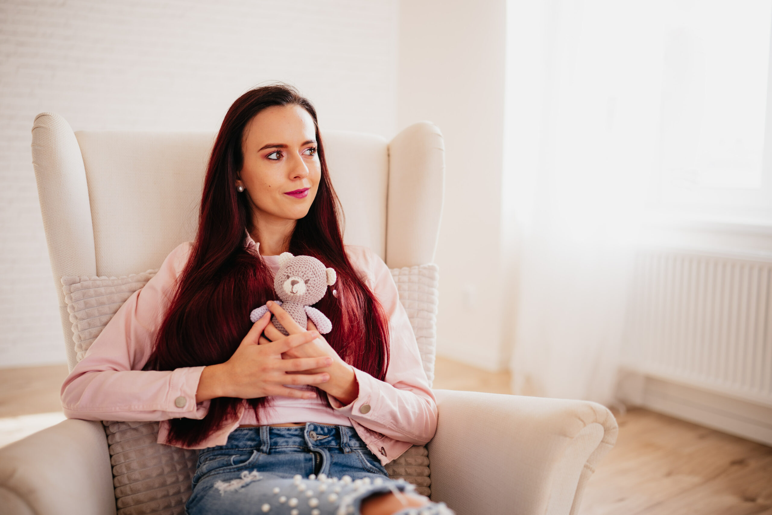 Žena držící v ruce medvídka přemýšlí o miminku.